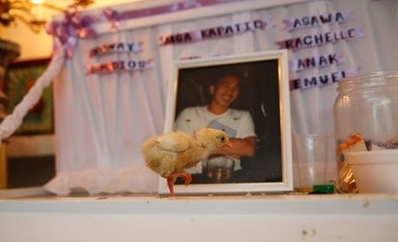 　９月５日、マニラ市内のスラム街では、２２歳の輪タク運転手Eric Sisonさんの遺体が棺に横たわり、その近くをヒヨコが行き交っている。地元の伝統にのっとり、彼を殺害した者の良心をつついて責める象徴として放されたのだ。写真はSisonさんの棺。マニラ首都圏パサイ市で８月撮影（２０１６年　ロイター/Erik De Castro）