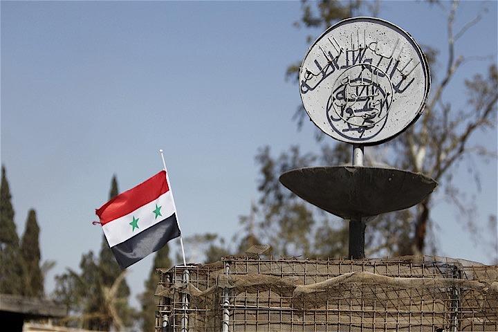 シリア北部マンビジュで16日、自爆攻撃があり、米軍関係者4人が死亡した。監視団体によると、死者は合わせて19人に上るという。写真は2016年パルミラを占拠したISのスローガンとシリア国旗。Omar Sanadiki - REUTERS