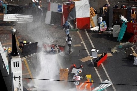 　５月２９日、ベネズエラの首都カラカスで、反政府デモに参加した野党指導者２人が、デモを鎮圧しようとした治安当局者にけがを負わされた。写真は放水で行進を妨げられるデモ参加者、カラカスで撮影（２０１７年　ロイター/Carlos Garcia Rawlins）