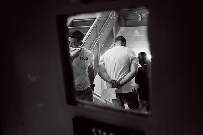 審問後に手錠をかけられる移民。彼らの多くに犯罪歴はなく、制度に従って出頭している