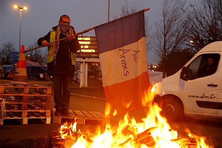 12月5日、フランスのマクロン政権は、来年1月に予定していた燃料税の引き上げを6カ月延期するとした前日の発表に続き、さらに来年いっぱい増税を見送ることを決めた。写真は国旗を燃やす増税反対のデモ参加者。フォンテーヌノートルダムで4日撮影（2018年　ロイター/Pascal Rossignol）