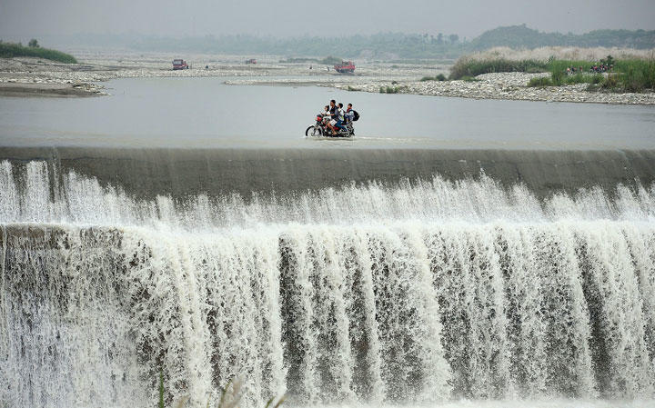 中国四川省で洪水により橋が流された後、川をバイクで渡る住民（写真は本文と関係ありません）　REUTERS