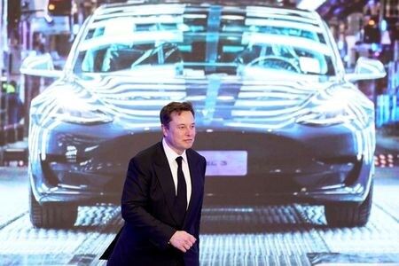 米電気自動車（ＥＶ）テスラのイーロン・マスク最高経営責任者（ＣＥＯ）は２２日に開催した電池の新技術を発表する「バッテリー・デー」で、ＥＶの価格を大幅に引き下げ、完全な自律走行性能を持つ価格２万５０００ドルのＥＶを３年以内に製造すると発表した。写真は今年1月、上海でスクリーンに映されたModel 3の映像の前を歩くイーロン・マスクCEO。（2020年 ロイター/Aly Song/File Photo ）