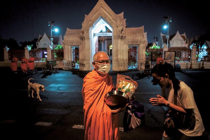 市民から供物を受け取る托鉢僧もマスク姿（バンコク、2月5日）　ATHIT PERAWONGMETHA-REUTERS