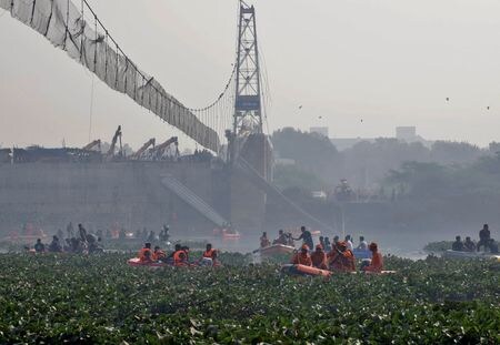 インド西部グジャラート州モルビで３０日起きた歩道用つり橋崩落事故で、死者数は少なくとも１３４人となり、３１日朝までに約１７０人が救出された。地元警察は３１日、つり橋の運営や改修工事に関わっていた業者ら９人を逮捕した。写真は１０月３１日、事故が起きた吊り橋の周辺で生存者の捜索活動を続ける救急隊（２０２２年　ロイター）
