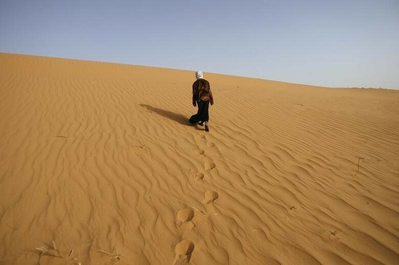 ２月２４日、複数の国際団体が地中海を横断して欧州に向かう途中で溺死した移民の数を調査しているが、サハラ砂漠での死者数は誰もカウントしていない。写真はサハラ砂漠のはずれにある、アルジェリアのティミムンで砂の上を歩く少女。２００８年３月撮影（２０１６年　ロイター/Zohra Bensemra）