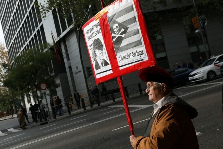 １１月２日、ベルギーに滞在中のカタルーニャ自治州のプチデモン元首相（写真）にスペインは逮捕令状を発行する見込み。写真はマドリッドの裁判所前でプラカードを掲げる男性（２０１７年　ロイター/Susana Vera）