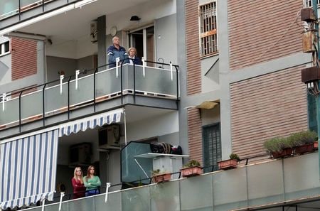 　３月２９日、イタリアで２９日に新型コロナウイルスの感染で死亡した人は、２日連続で前日水準を下回った。写真はイタリアのナポリで、近隣の教会の屋上で行われているミサに参加する人々（２０２０年　ロイター/Ciro De Luca）