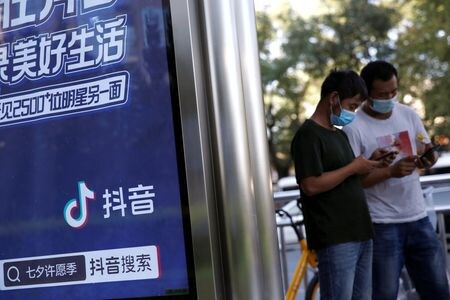 １２月１３日、    中国政府系シンクタンク、信息通信研究院（ＣＡＩＣＴ）は、１１月のスマートフォン（スマホ）の国内向け出荷が前年比２５．７％増の３４８０万台だったと発表した。写真は８月。北京でスマホを見る男性（２０２１年　ロイター/Tingshu Wang）