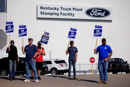 　米フォード・モーターは、全米自動車労働組合（ＵＡＷ）との労使交渉で暫定合意に達し、労組執行部の承認待ちとなっている。事情に詳しい３人の関係筋が２５日、明らかにした。写真は１２日、ケンタッキー州ルイビルにあるフォードの工場前でピケを張るＵＡＷの組合員（２０２３年　ロイター／Luke Sharrett）