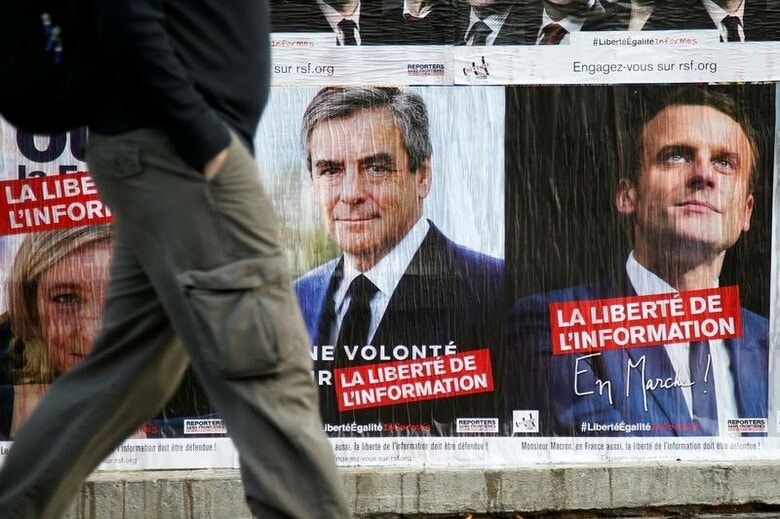 ４月６日、最新の世論調査によると、フランス大統領選は中道系独立候補のマクロン前経済相と極右政党・国民戦線（ＦＮ）のルペン党首が依然リードを保っている。ただ、急進左派のメランション氏が急速に追い上げていることも明らかになった。写真は大統領候補らのポスター。パリで５日撮影（２０１７年　ロイター/Charles Platiau）