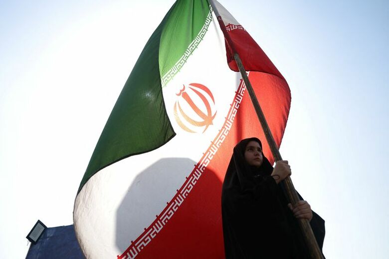 写真はテヘランの路上でイラン国旗を掲げる女性。6月10日撮影。提供写真。Majid Asgaripour/WANA (West Asia News Agency) via REUTERS