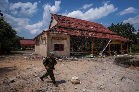 　１１月１４日、タイとカンボジア間で係争中の国境で１０日に発生した地雷爆発について、東南アジア諸国連合（ＡＳＥＡＮ）のオブザーバーが現地調査する。写真は、停戦後に両国の国境沿いの被害地域を視察するため外交使節団が訪問した際、砲撃で損傷した建物の前を歩くカンボジア兵。カンボジアのオッドーミアンチェイで８月撮影（２０２５年　ロイター/Soveit Yarn）