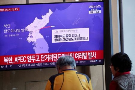 2025年10月22日、韓国ソウルの鉄道駅で、北朝鮮が短距離弾道ミサイルを発射したというニュースを放送するテレビを見る人々。   REUTERS/Kim Hong-Ji