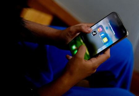 　オーストラリア政府は昨年、１６歳未満の子どもによる交流サイト（ＳＮＳ）利用を禁止する法律を可決した際、米アルファベット傘下の動画投稿サイト「ユーチューブ」は適用除外とした。写真は、ＳＮＳアプリを携帯で見る高校生。２０２４年１１月２８日、（２０２５年　ロイター/Asanka Brendon Ratnayake）