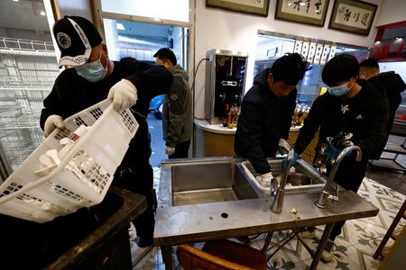 　３月２１日、中国の首都北京の郊外にある荒れ果てた倉庫で、中古厨房機器の販売業を手がけるアン・ダウェイさん（３８）は飲食店向けの巨大な冷蔵庫と業務用コンロ、パン焼きオーブンの列を点検していた。写真は２月、閉店した北京の飲食店から厨房機材を回収するアンさんのチーム（２０２５年　ロイター/Tingshu Wang）