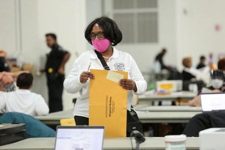 １１月５日、米首都ワシントンの連邦地裁のエメット・サリバン判事は、米郵政公社（ＵＳＰＳ）に対して、大統領選の郵便投票の集計を続けている州で、未配達の投票用紙がないかどうか１日２回総点検するよう命じた。デトロイトの開票所で４日撮影（２０２０年　ロイター/Rebecca Cook）