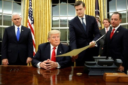　２月７日、米ホワイトハウスのロブ・ポーター補佐官が、辞任を表明した。時期は明らかにしなかった。同補佐官を巡っては、メディアが虐待に遭っていたとする２人の元妻の証言を報じていた。写真はトランプ大統領（左から２人目）に書類を手渡すポーター補佐官（左から３人目）。昨年１月、ホワイトハウスで撮影（２０１８年　ロイター／Jonathan Ernst）