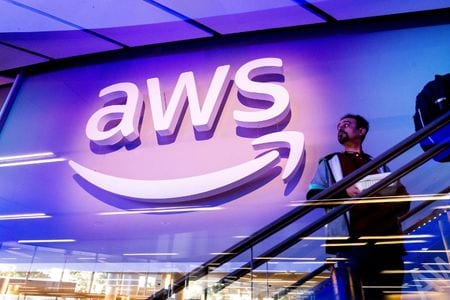 写真は、AWSのロゴの前を通り過ぎるAWS re:Invent 2025の会議参加者。2025年12月1日、米国ネバダ州ラスベガスで撮影。REUTERS/Noah Berger
