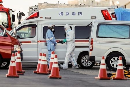 日本では２２日、横浜港に停泊するクルーズ船「ダイヤモンド・プリンセス」から下船した乗客にも感染が確認された。写真は同船が停泊した横浜・大黒ふ頭で防護服を着用して作業する係員たち。６日撮影。（２０２０年　ロイター／Kim Kyung-Hoon)