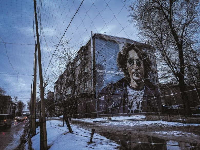ロシア軍の攻撃で損傷したジョン・レノンの壁画。街はウクライナ軍の駐屯地となり、通りにはドローン対策の防護ネットが作られた（26年1月、 ハリコフ州イジューム）　TAKASHI OZAKI