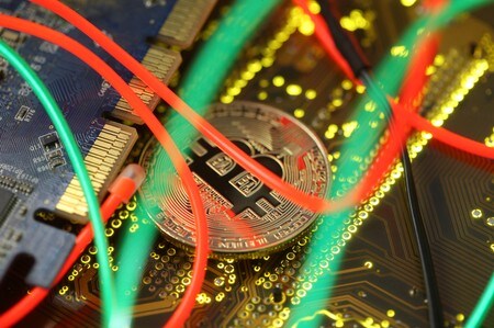 　２月２２日、ブロックチェーン技術（分散台帳技術）を応用すれば、デジタル通貨にマイナス金利やプラスの金利を付与することができ、現在の金融政策よりもダイレクトに効果が出る──。中島真志・麗澤大学教授は、金融政策に新たな政策手段を加えることが可能との見方を示す。写真はブロックチェーン技術が支えている仮想通貨のビットコイン。３日撮影（2018年　ロイター／Dado Ruvic）