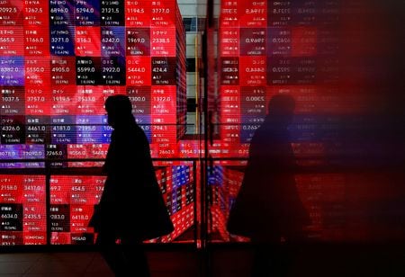 　１１月２５日、東京株式市場で日経平均は、前営業日比４９６円２９銭高の３万８７８０円１４銭と続伸して取引を終えた。写真は株価ボードの前を歩く人。２月、都内で撮影（２０２４年　ロイター/Issei Kato）