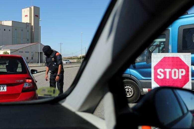 スペイン北西部のガリシア地方は7月5日、新型コロナウイルス感染者の増加を受け、約7万人の住民を対象に封鎖措置を再導入した。前日には北東部カタルーニャ州でも一部地域で行動制限が再び導入された。写真は移動許可証を検査する警官。4日、カタルーニャ州リェイダで撮影(2020年　ロイター/Nacho Doce)
