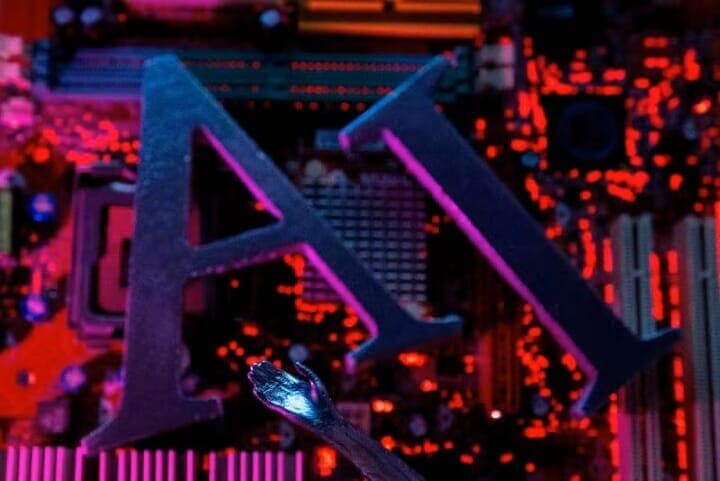 半導体業界では大手メーカーが人工知能（ＡＩ）向け製品の生産を急拡大したため、スマートフォンやコンピューター、サーバーに使われる汎用製品の供給がひっ迫し、一部でパニック的な買い付けや価格高騰が起きている。写真はＡＩの文字とコンピューターの基盤のイメージ。２０２３年６月、ボスニア・ヘルツェゴビナのゼニカ市で撮影（２０２５年　ロイター/Dado Ruvic）