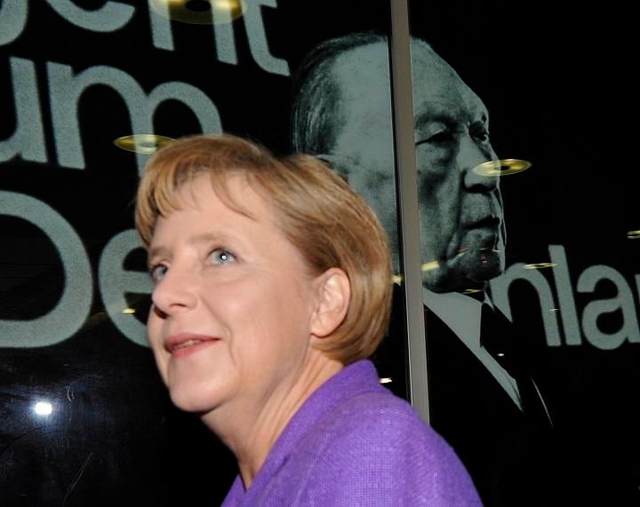 CDU党本部にあるアデナウアー元首相の写真の前を通るメルケル首相（09年）　REUTERS/Wolfgang Rattay