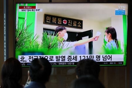 ５月２７日、北朝鮮では２６日午後６時時点で、約１０万０４６０人が新たに発熱症状を示した。写真は１７日、韓国・ソウルで、北朝鮮での感染状況を伝えるニュースを見る人々（２０２２年　ロイター/Kim Hong-Ji）