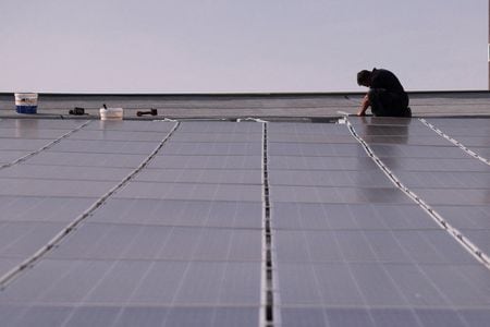 イタリア送電会社テルナは１８日付のリポートで、国内で再生可能エネルギーによる発電量が、今年上半期（１─６月）に化石燃料由来の発電を初めて上回ったと明らかにした。写真はソーラーパネルの作業をする男性でミラノで４月に撮影（２０２４年　ロイター／Claudia Greco）
