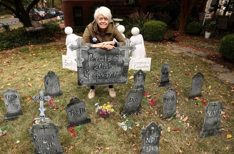 米首都ワシントンは民主党の支持者が圧倒的に多く、一部地域では政治色の濃いハロウィーンの飾り付けが長年の風物詩となっている。写真は墓石の形をしたプレートと、制作者の現地住民ドナ・ブレスリンさん。１０月２９日撮影（２０２５年　ロイター/Kevin Lamarque）