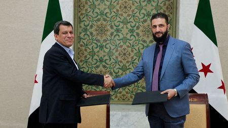 　３月１０日、クルド人勢力主体の民兵組織「シリア民主軍」（ＳＤＦ）は、シリア暫定政府に合流するため、同政府との合意文書に署名した。写真は、シャラア暫定大統領（左）とＳＤＦのアブディ司令官（右）。同日、ダマスカスで撮影。SANA提供（２０２５年　ロイター）