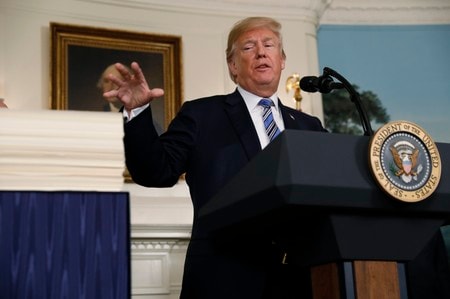 ３月２３日、トランプ米大統領は連邦政府の９月末までの支出を賄う１兆３０００億ドルの包括的歳出法案に署名し、同法は成立した。写真は２３日、歳出法案を横に置き、記者会見するトランプ大統領。ワシントンで撮影（２０１８年　ロイター／Kevin Lamarque）