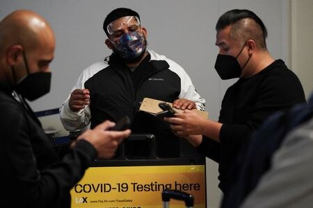 　米航空大手や旅行業界団体などは５月５日、新型コロナウイルスワクチンを接種済みの空路入国者を対象に、出発前の検査義務を廃止するようホワイトハウスに要請した。写真は検査を受ける旅行者、２０２１年１２月にロサンゼルス空港で撮影（２０２２年　ロイター/Bing Guan）