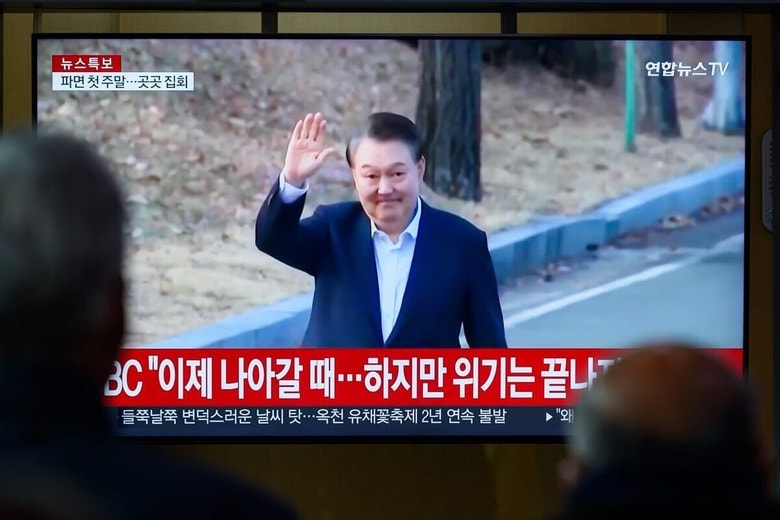 尹が支持者に手を振るニュース映像を見る人々　Kim Jae-Hwan / SOPA Images via Reuters Connect