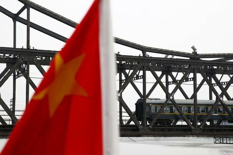 ９月８日、中国は米国のように北朝鮮の怒りの矛先にされるのではないかと、一部の外交官や専門家が危惧するほどに、中朝関係は急速に悪化している。写真は中国の国旗と、同国丹東から北朝鮮の新義州をつなぐ友好橋を渡る旅客列車。丹東で昨年９月撮影（２０１７年　ロイターS/Thomas Peter）