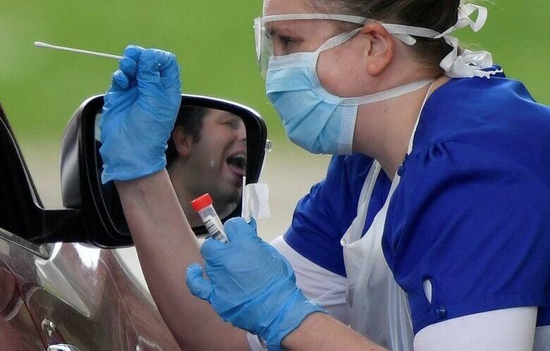 写真は2日、英チェシントンで新型コロナウイルスの検査を行う医療関係者（2020年　ロイター/Toby Melville）