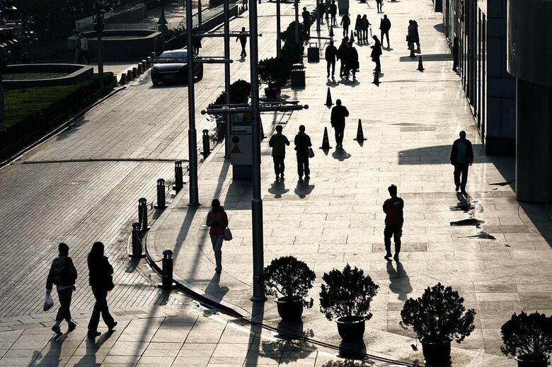 写真は北京市内のオフィスビルとショッピングモールが入る複合施設の前を歩く人々。2024年4月撮影。REUTERS/Tingshu Wang