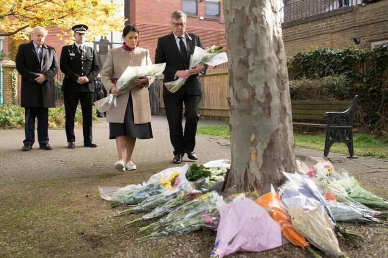 英ロンドン近郊で10月にトラックのコンテナから39人の遺体が発見された事件で、捜査当局は、犠牲者全員がベトナム出身で身元が確認されたと明らかにした。写真は英グレイズで献花する警察署長らとジョンソン英首相（左）。10月28日、代表撮影（2019年　ロイター/Stefan Rousseau）