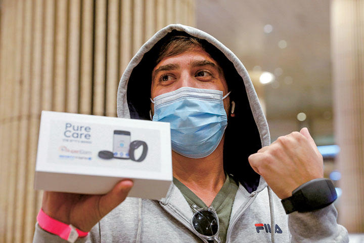 空港で電子ブレスレットを見せる旅行客　Amir Cohen-REUTERS