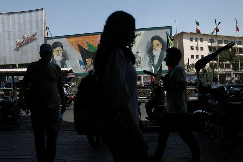 6月9日、テヘランで、指導者が描かれた壁画の前を行きかう人々。Majid Asgaripour/WANA (West Asia News Agency) via REUTERS