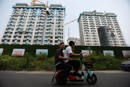 中国政府の顧問は来年の経済成長目標を４．５─５．５％とすることを来月の中央経済工作会議で提案する見通し。写真は建設中の住宅の前をスクーターで通り過ぎる人で北京で９月に撮影（２０２３年　ロイター／Tingshu Wang）