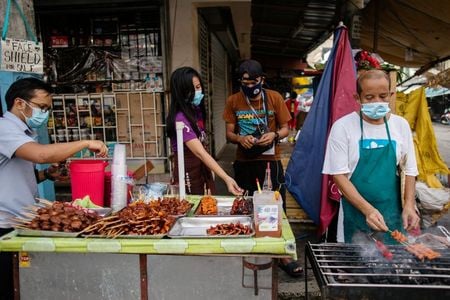 　８月１３日、フィリピン大統領府の報道官によると、同国は１０月にもロシア製新型コロナウイルスワクチンの臨床試験を開始する計画。写真はマスクをして働く露天商。マニラで１０日撮影（２０２０年　ロイター／Eloisa Lopez）