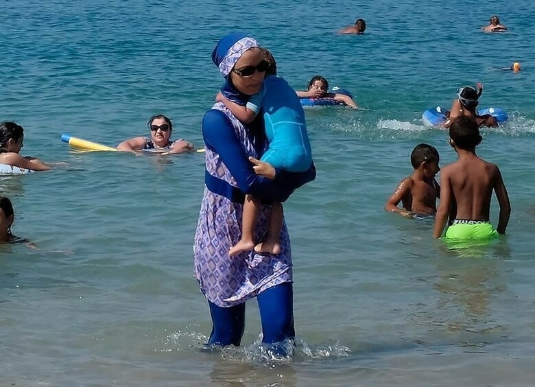 A woman wearing a burkini walks in the water August 27, 2016 on a beach in Marseille, France, the day after the country\'s highest administrative court suspended a ban on full-body burkini swimsuits that has outraged Muslims and opened divisions within the