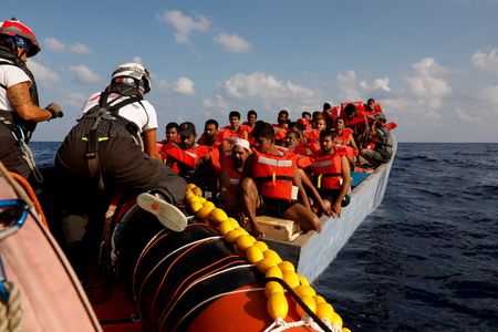 　移民の救助に携わる非営利団体から、地中海で遭難した船の漂流地点を特定するアプリを設計できないかと相談されたドイツ人ウェブ開発者ニク・ゼムケ氏（３２）は、世界最大級のハッカー集団「カオス・コンピューター・クラブ（ＣＣＣ）」がドイツ北部の都市ハンブルクで開いた年次総会に出向き、志を同じくするボランティアを見つけ出した。写真はリビア沖の国際水域で、木造の船から救出される６１人の移民。２０２３年９月撮影（２０２４年　ロイター/Darrin Zammit Lupi）