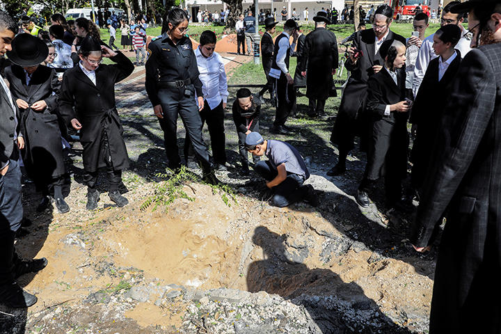 ガザ地区から着弾したロケット弾の周囲を囲むイスラエル市民（5月19日、アシュドッド）　Baz Ratner-REUTERS