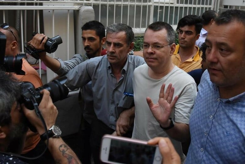 ７月２５日、トルコの裁判所は、テロリズムやスパイの罪に問われ係争中の米国人アンドリュー・ブランソン牧師について、先週の収監継続決定を撤回し、自宅謹慎措置に変更した。写真は釈放され自宅前に到着した同牧師と付き添う当局者たち(２０１８年　ロイター)