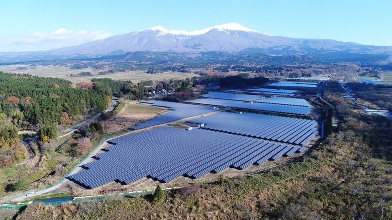 庄内遊佐太陽光発電所　奥に写る鳥海山からの伏流水がすぐ近くの月光川を流れ遊佐町の田んぼに流れているため、発電所では除草剤を一切使わない